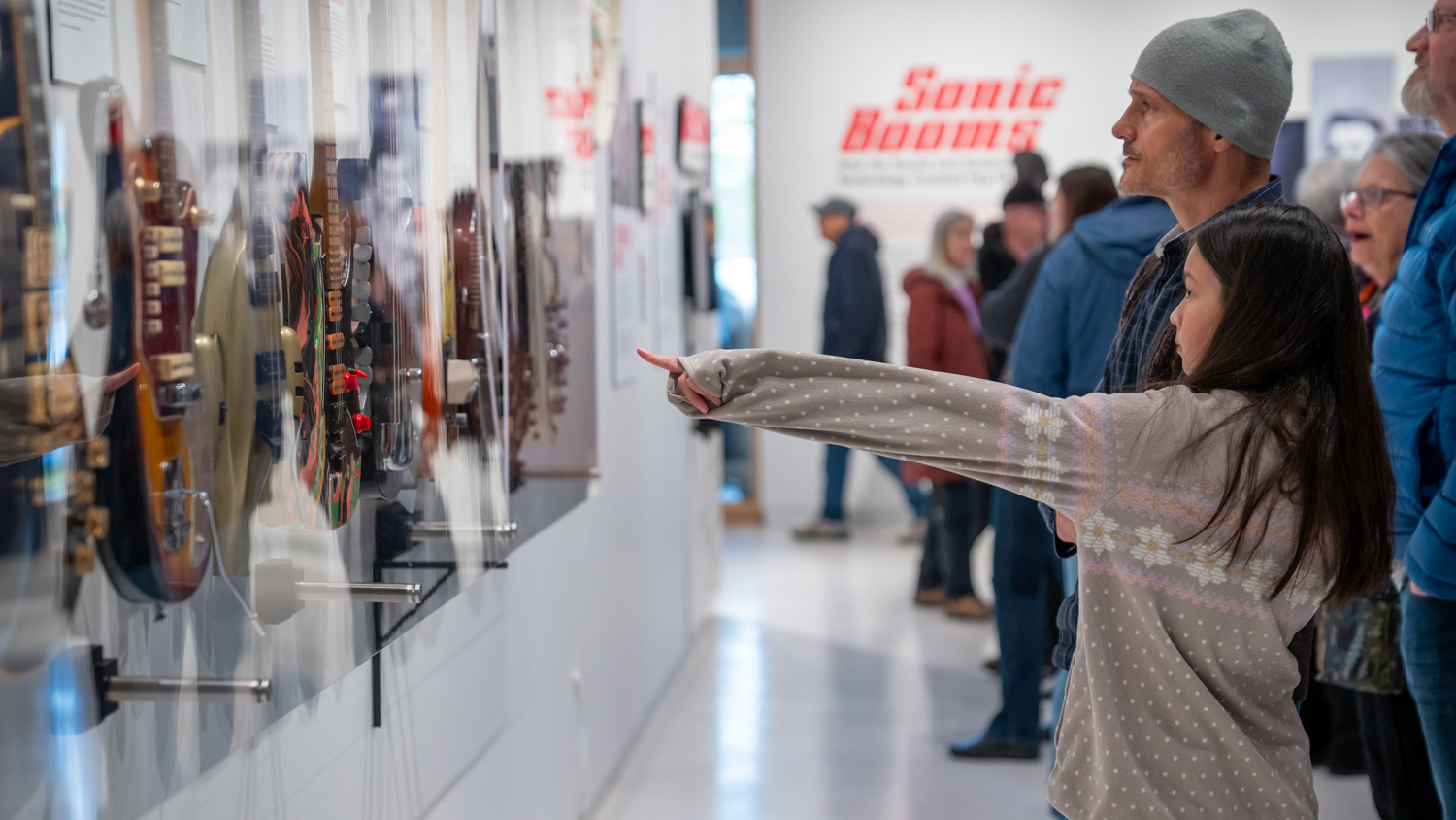 young girl pointing to guitars in the sonic booms exhibition