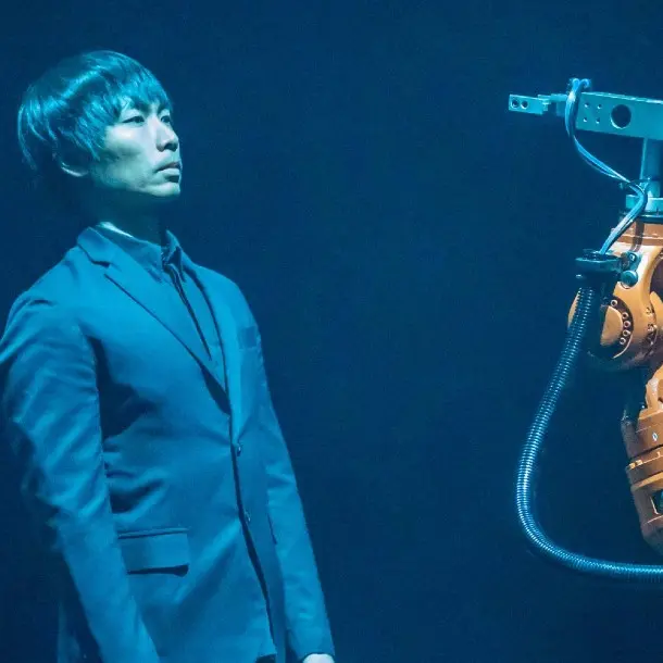 man standing and leaning back while looking at robot in face