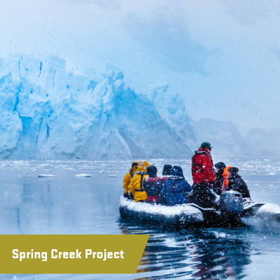 Explorers in a dingy in front of a glacier 